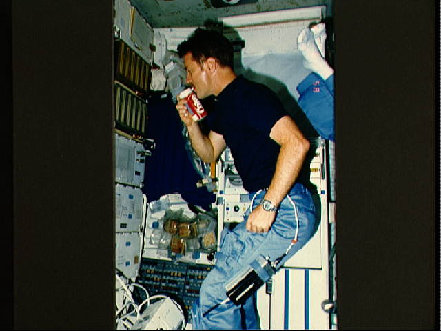Anthony England drinking a soft drink in the Space Shuttle Challenger