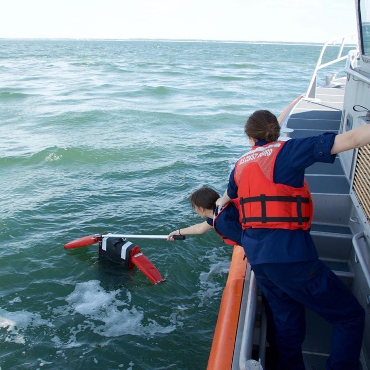A practice dummy is fished out of the water by two Coast Guard rescuers
